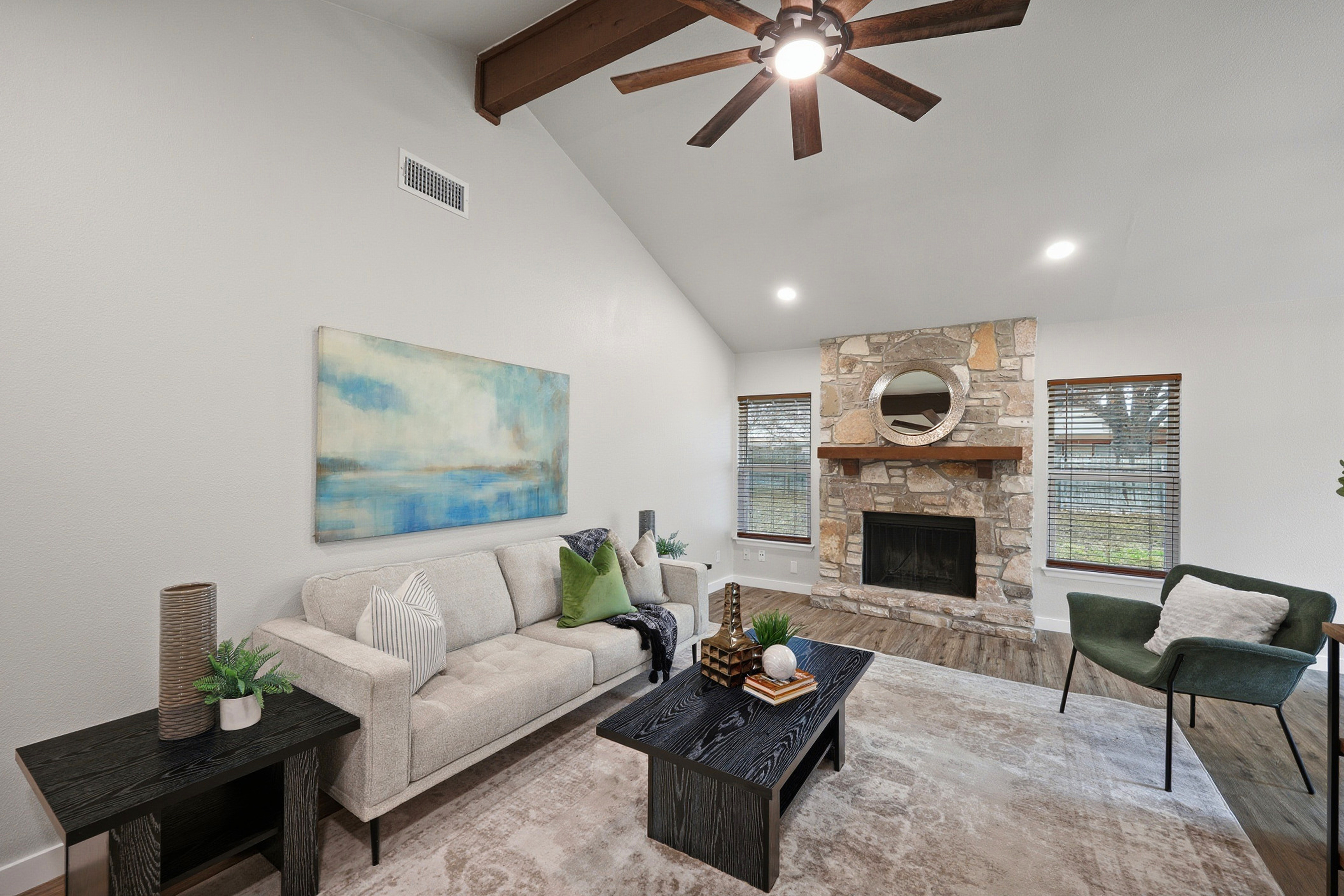 High vaulted family room open to kitchen and dining, with wood beams and LVP floors